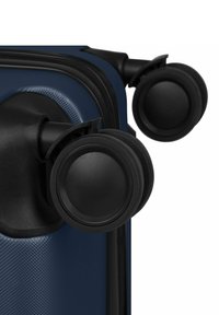 Deux roues doubles noires pivotantes fixées à l'angle d'une valise texturée bleu foncé.