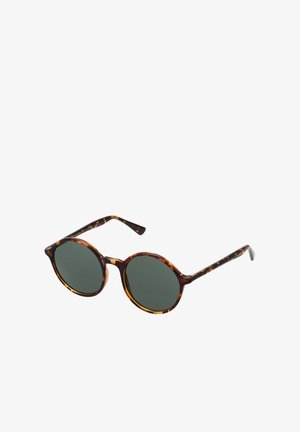 Lunettes de soleil rondes avec des verres vert foncé et des montures et branches à motif écaille de tortue sur fond blanc.