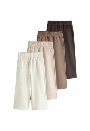 Fire par elastiske taljebukser i beige, lyse beige, brun og mørkebrun, arrangeret overlappende på en hvid baggrund.