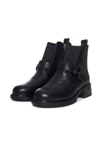 Bottines en cuir noir avec des panneaux latéraux en élastique et une fermeture éclair sur le côté. Présente une sangle décorative avec un accent métallique circulaire et un talon bloc.