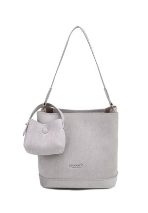 Sac seau en daim gris clair avec une longue bandoulière et une petite pochette attachée avec une fermeture à bouton-pression.
