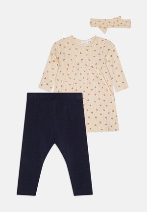 Beige babykjole med lange ærmer med lille rødt blomsterprint, marineblå leggings og matchende beige hårbånd med røde blomster.
