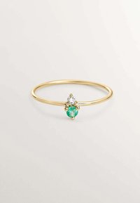 Anillo de oro con una banda delgada, que presenta un zafiro redondo y un diamante en forma de pera encima. Textura suave con engastes de garras para las piedras.