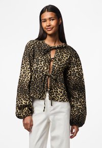 Halenka s leopardím potiskem v černé a hnědé barvě, se zavazováním u krku, puffovými rukávy a zkráceným lemem. Vyrobena z hladkého materiálu.