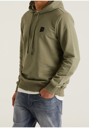 Sudadera con capucha verde oliva hecha de tejido suave, con un bolsillo frontal y un parche de logo cuadrado negro en el pecho.