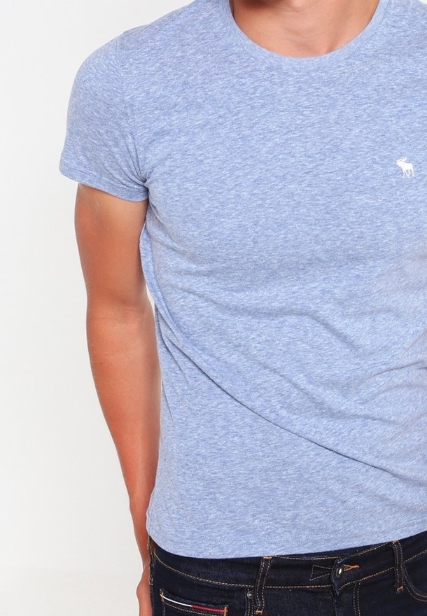 Lichtblauw, korte mouwen, ronde hals t-shirt van zachte stof; heeft een klein wit logo op de borst en is aansluitend.