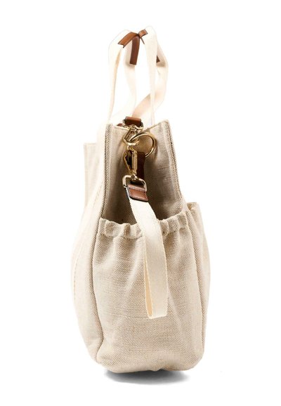Sac fourre-tout en toile beige avec poche latérale élastique, bandoulière réglable et fermoirs en métal doré avec accents en cuir marron.