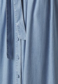 Ljusblå denimklänning med knappslå, midjeband och subtil struktur. Mjuk tyg med en avslappnad passform.