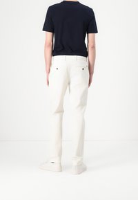 Bílé bavlněné kalhoty rovného střihu s poutky na opasek a dvěma zadními kapsami, v kombinaci s námořnickou modrou tričkem s krátkým rukávem.