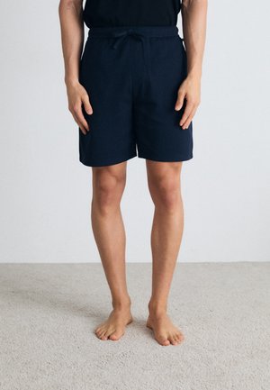 Pantalones cortos de color azul marino, hechos de una tela suave, con una cinturilla elástica y cordón ajustable, de corte recto y que terminan por encima de la rodilla.