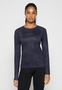 Długorękawowa sportowa koszulka w ciemnym granatowym kolorze, wykonana z gładkiej, fakturowanej tkaniny, ze ściągaczem przy szyi i rękawami raglanowymi. Bez widocznych logo ani wzorów.