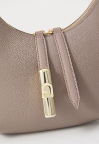 Borsa a mano in pelle taupe con una sottile texture, dotata di una zip e una chiusura in tono oro. Due manici piatti in pelle si estendono dalla chiusura.