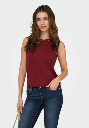Bordeaux mouwloze top van zachte stof, met een ronde halslijn en geribde zoom, gecombineerd met donkerblauwe jeans. Eenvoudig ontwerp.