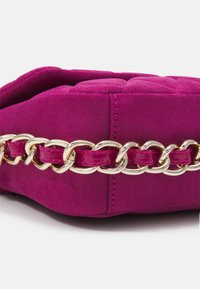 Borsa a mano in suede fucsia con texture trapuntata, caratterizzata da una tracolla in catena mista di rosa lucido e oro. Forma morbida e rettangolare con dettagli cuciti.