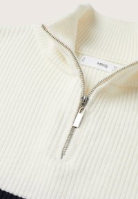 White ribbed knit sweater featuring a zippered collar and a silver zipper detail. Tag with brand name visible inside the collar.