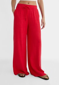 Rote, weit geschnittene Hosen aus leichtem Stoff, mit einem elastischen Bund und Kordelzug sowie knielangen Säumen.