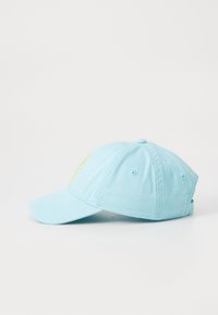 Light blue cotton cap with a curved brim, rear adjustment strap, and yellow lettering on the front. Soft texture, casual design.