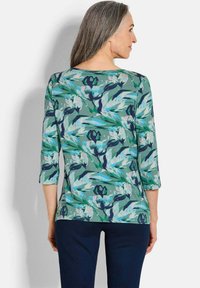 Bluse mit Blumenmuster in Grün mit blauen, weißen und schwarzen Akzenten. Aus weichem, leichtem Material mit lässiger Passform und Rundhalsausschnitt.