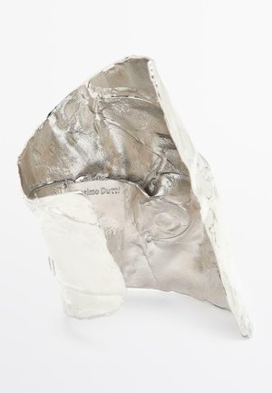 Sculpture abstraite argentée métallique au design froissé, présentant des surfaces lisses et texturées ainsi que des arêtes vives. Marquage notable à l'intérieur.