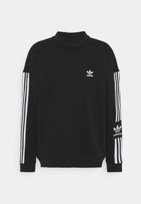 Felpa nera con collo alto, logo bianco Adidas sul petto e tre strisce bianche lungo le maniche. Tessuto morbido.