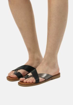 Sandalias negras y metálicas con tiras cruzadas, suela plana y parte superior texturizada. Diseño abierto que muestra los dedos y los pies.