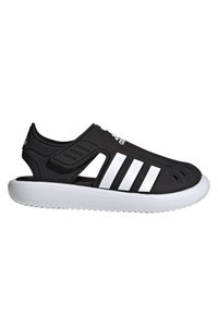 Sorte slip-on sko laget av syntetisk materiale med hvite striper og teksturerte detaljer. Har åpen hæl og ventilasjonshull.