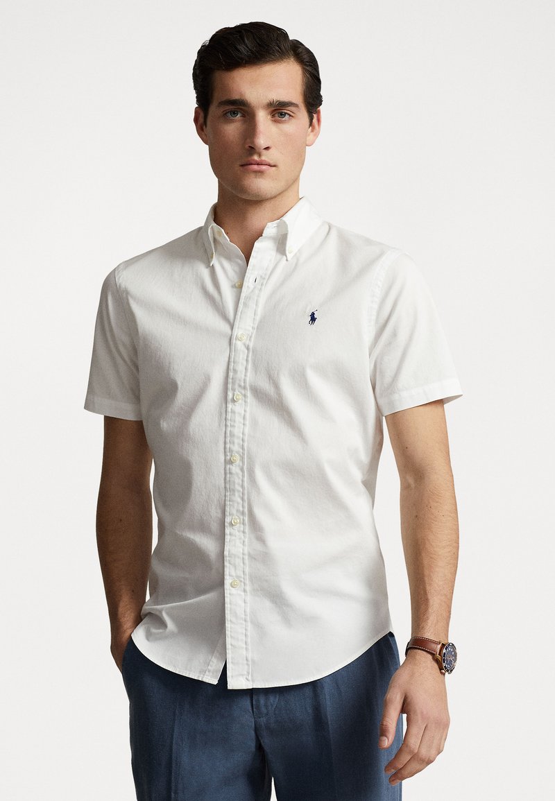 Chemise blanche à manches courtes avec boutons, en coton, dotée d'un petit logo bleu marine sur la poitrine gauche et d'un col classique.