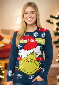 Maglione tricot navy con grande grafica del Grinch, accenti rossi con fiocchi di neve e testo che dice "Chi? Io? Grinchy?" in colori vivaci.