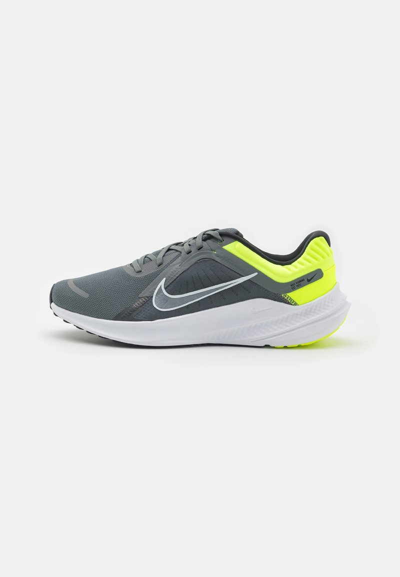 Chaussure de course Nike grise et jaune néon avec semelle blanche et logo Swoosh noir, vue de côté sur fond blanc.