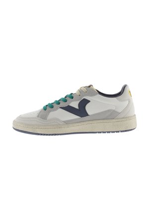 Zapatilla baja con parte superior de cuero blanco y acentos de ante gris, cordones verdes y logotipo azul marino. Suela de goma texturizada, diseño minimalista.