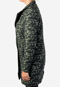 Abrigo largo negro con un patrón de camuflaje verde texturizado, solapas muescas y bolsillos laterales. Tela suave con un acabado liso.