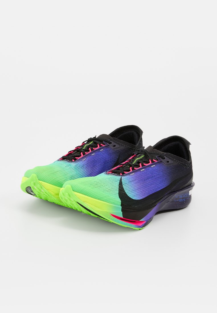 Par de zapatillas de running de corte bajo con tejido degradado de verde a púrpura, logo negro de Nike, suelas verde neón y cordones rosas y negros sobre fondo blanco.