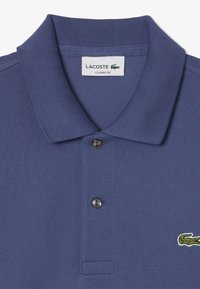Polo blu navy in tessuto testurizzato, con colletto classico, chiusura a due bottoni e logo di un coccodrillo ricamato sul lato sinistro del petto.