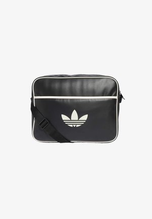 Čierna kožená messenger taška s bielym lemovaním a veľkým off-white logom Adidas vpredu. Nastaviteľný čierny popruh. Hladká textúra.