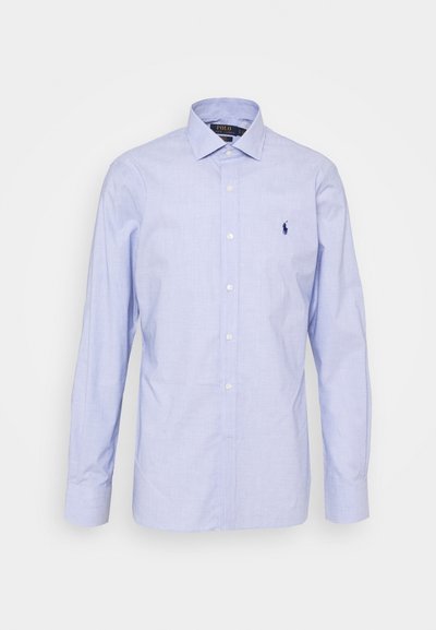 Svetlo modra dolgi rokav s srajčno zapenjanje v mehkem materialu. Ima klasičen ovratnik, sprednji zadrgo in majhen vezen logotip na prsih.