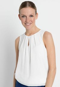 Weißes ärmelloses Blusenshirt mit runder Ausschnitt, das eine vordere Falte und ein kleines Schlüssellochdetail am Ausschnitt aufweist. Glatte Stoffstruktur.