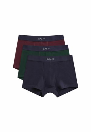 Drie paar herenboxershorts gestapeld, in marineblauw, donkergroen en bordeauxrood, elk met een zwarte tailleband met het label "GANT" in het wit.