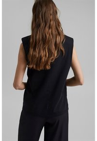 Top nero senza maniche con scollatura rotonda. Tessuto liscio, silhouette dritta e design posteriore pulito, adatto per l'abbigliamento casual.