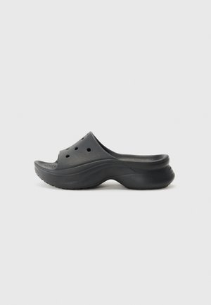 Zoccoli neri slip-on in gomma con design curvo, dotati di fori di ventilazione e suola esterna testurizzata per una migliore aderenza.