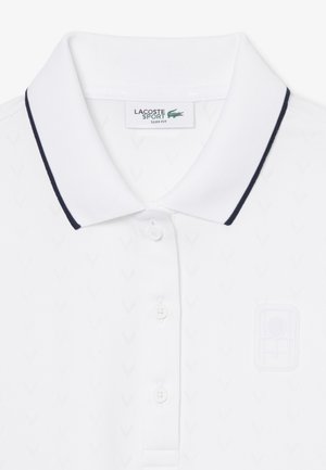 Polo bianca a maniche corte con motivo a rilievo, tre bottoni, dettagli del colletto blu navy e un logo discreto sul petto.