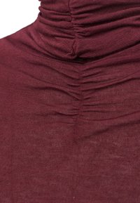 Burgunderfarbener Rollkragenpullover mit geraffter Textur am Hals und der Brust, aus weichem, leichtem Stoff mit glatter Oberfläche.