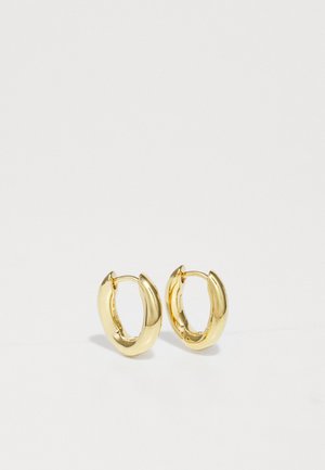 Goldene Creolen mit einem geschwungenen, massiven Design. Glatte metallische Oberfläche, offene Enden für einfaches Tragen und ein dezenter Glanz verleihen ihnen ein ansprechendes Erscheinungsbild.