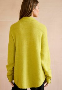 Jasnozielony, oversize sweter o teksturowanym wykończeniu, z kołnierzem i opadającymi ramionami, z zaokrąglonym dołem i ściągaczami na mankietach.