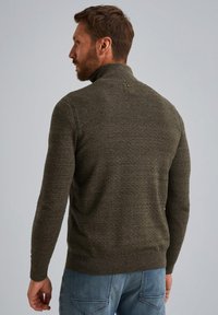 Donkergroen gebreide trui met een hoge kraag, geribbelde boorden en zoom, voorzien van een textuurpatroon en een kleine accentknop aan de achterkant.