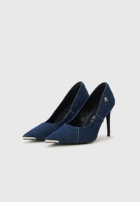 Chaussures à talons hauts en denim bleu foncé avec un bout pointu et des accents beiges. Présente un design �élégant et un talon aiguille. Petit logo sur le côté.