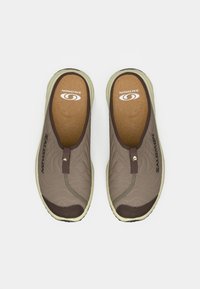 Brune slip-on sko med kviltet tekstur, gummisåle og en lys såle. Har en logo på innersålen og på siden.