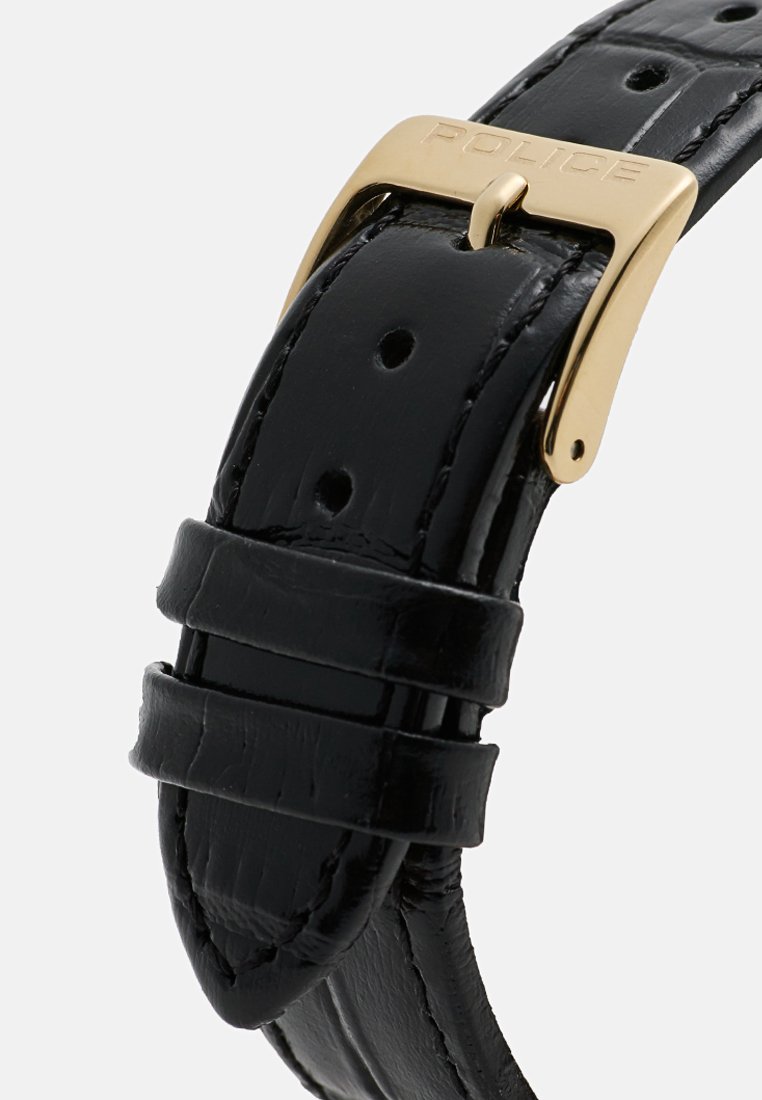 Correa de reloj de cuero negro con acabado texturizado, con hebilla de metal dorado grabada con "POLICE". Se observan múltiples agujeros de ajuste.