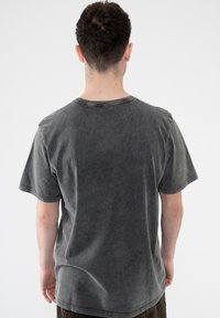 Gray, short-sleeve t-shirt with a faded, slightly distressed texture. Crew neckline and relaxed fit, with visible stitching at the edges.