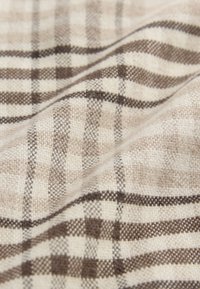 Tessuto a quadri beige e marrone con una finitura morbida e testurizzata. Presenta una trama alternata di quadrati grandi e piccoli.