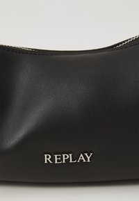 Borsa in pelle nera con una superficie liscia, caratterizzata da un logo argento "REPLAY" sul davanti e una chiusura con zip nella parte superiore.